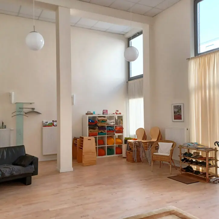 Seminarraum mieten in Winsen Luhe – ideal für Workshops & Einzelsitzungen. Auf dem Bild zu sehen, ein Bild vom Raum. Zu sehen ist Equipment wie z.B. Meditationskissen im Regal, Stühle und ein Sofa.